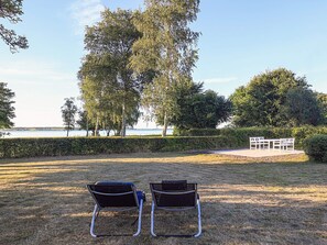 A grassy outdoor area with two metal chairs and a white table and chairs set. - 5 Person Holiday Home in Stubbekobing (Stubbekobing)