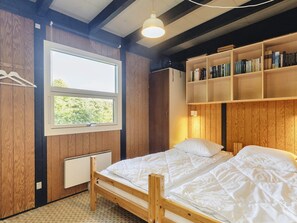 Une chambre à coucher avec un lit en bois, une fenêtre et une bibliothèque.