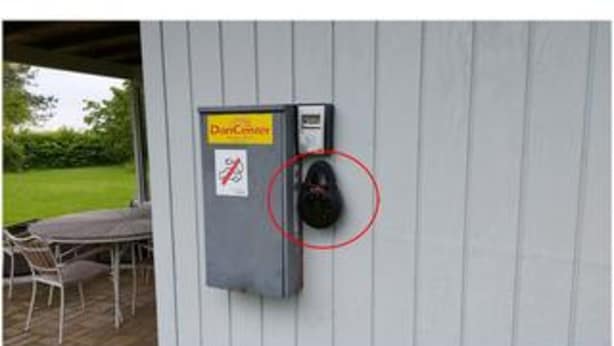 A utility box with a 'Pay Here' sign, a no-smoking sign, and a red circle highlighting a specific area. - 5 Person Holiday Home in Stubbekobing (Stubbekobing)