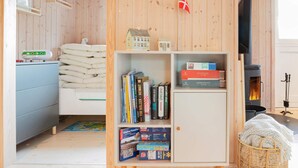 A cozy room with a bed, a bookshelf, a fireplace, and a small table with a kettle.