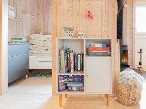 A cozy room with a bed, a bookshelf, a fireplace, and a small table with a kettle. - 5 Person Holiday Home in Dannemare (Dannemare)