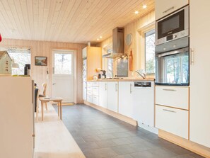 A modern kitchen with wooden cabinets, a Bosch oven, and a window overlooking a forest. - 5 Person Holiday Home in Dannemare (Dannemare)
