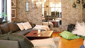 A living room with a sofa, a coffee table, a mirror, and a patterned wallpaper.