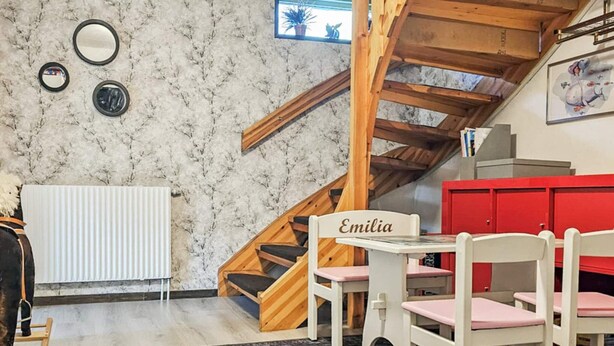A cozy room with a wooden staircase, a white radiator, a table with chairs, and a red cabinet. - 4 Star Holiday Home in Ullared (Ullared)