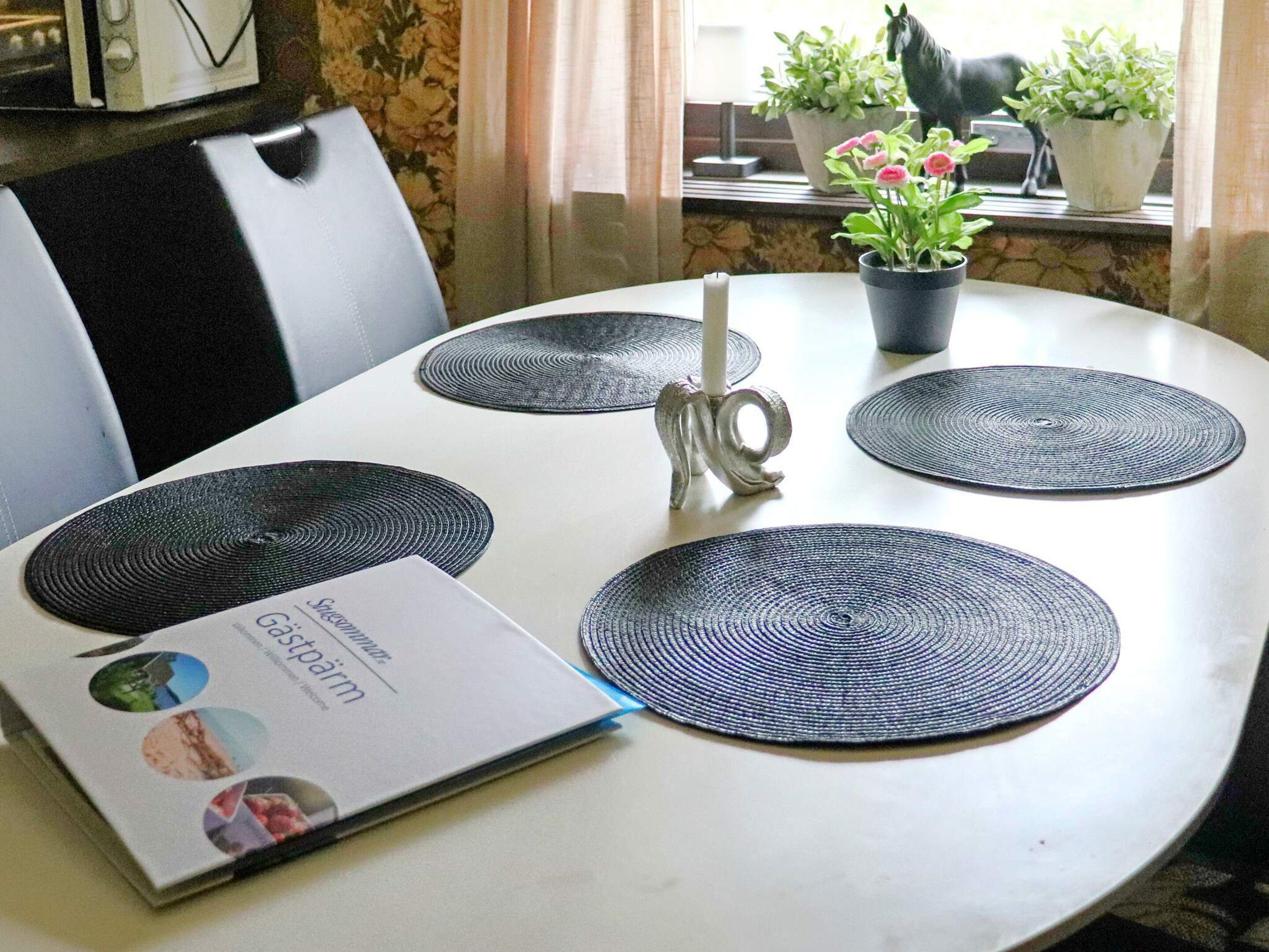 Una mesa de comedor con cuatro individuales circulares, una vela y un menú.
