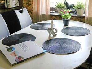 A dining table with four circular placemats, a candle, and a menu.