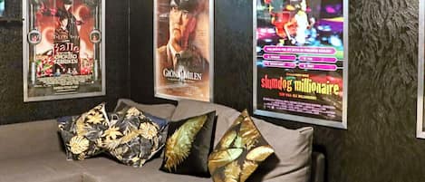 A room with a grey sofa and three posters on the wall.