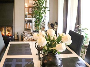 A dining table with a vase of white roses, a black decorative item, and a fireplace in the background. - 4 Star Holiday Home in Ullared (Ullared)