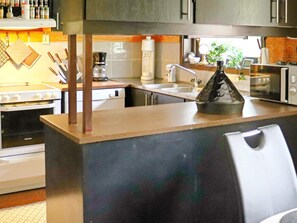 A kitchen with a central island, a stove, a microwave, and a sink. - 4 Star Holiday Home in Ullared (Ullared)