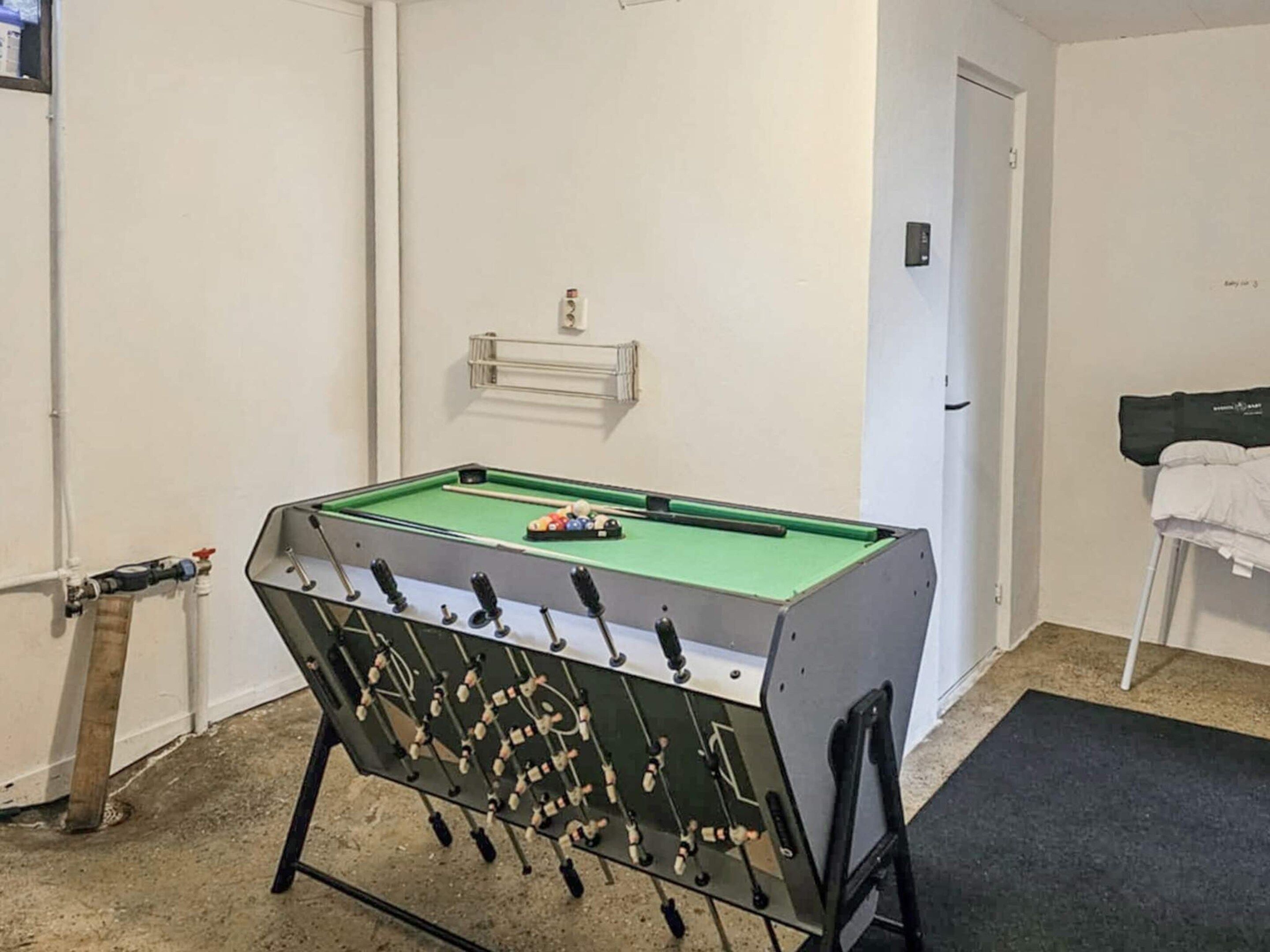A pool table in a room with white walls, a door, and a small shelf above it.