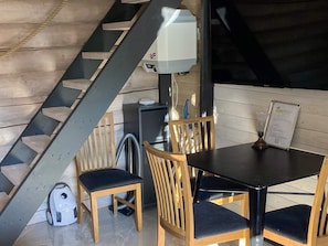 Ruokailutila, jossa on portaikko, puiset tuolit, pöytä ja menukorttiteline.