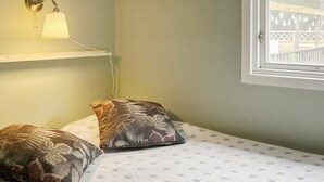 A room with a bed, two patterned pillows, a wall-mounted lamp, and a window with a view of a wooden deck. - 4 Star Holiday Home in Ingaro (Ingaro)