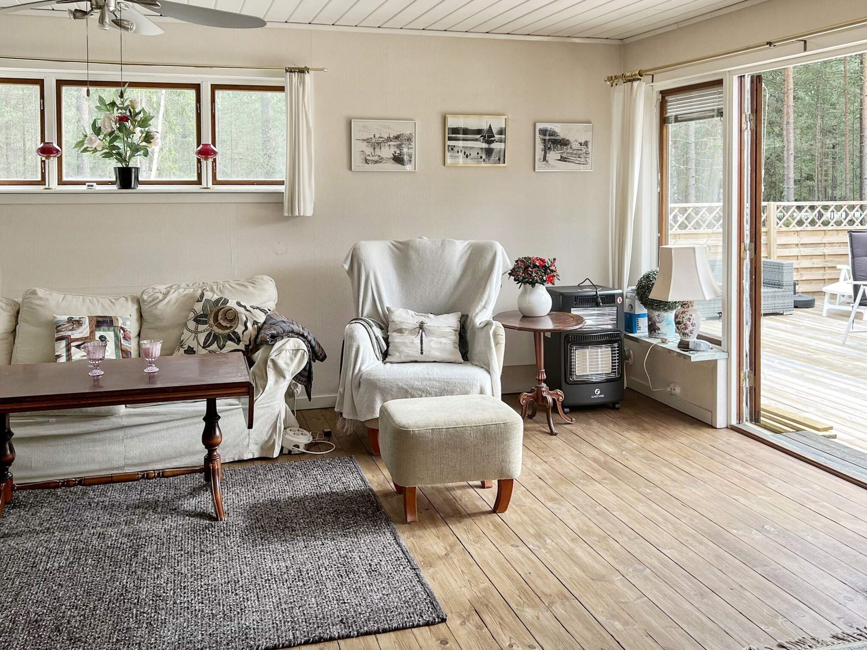 A cozy living room with a fireplace, a comfortable sofa, a wooden coffee table, and a large window offering a view of the outdoors.