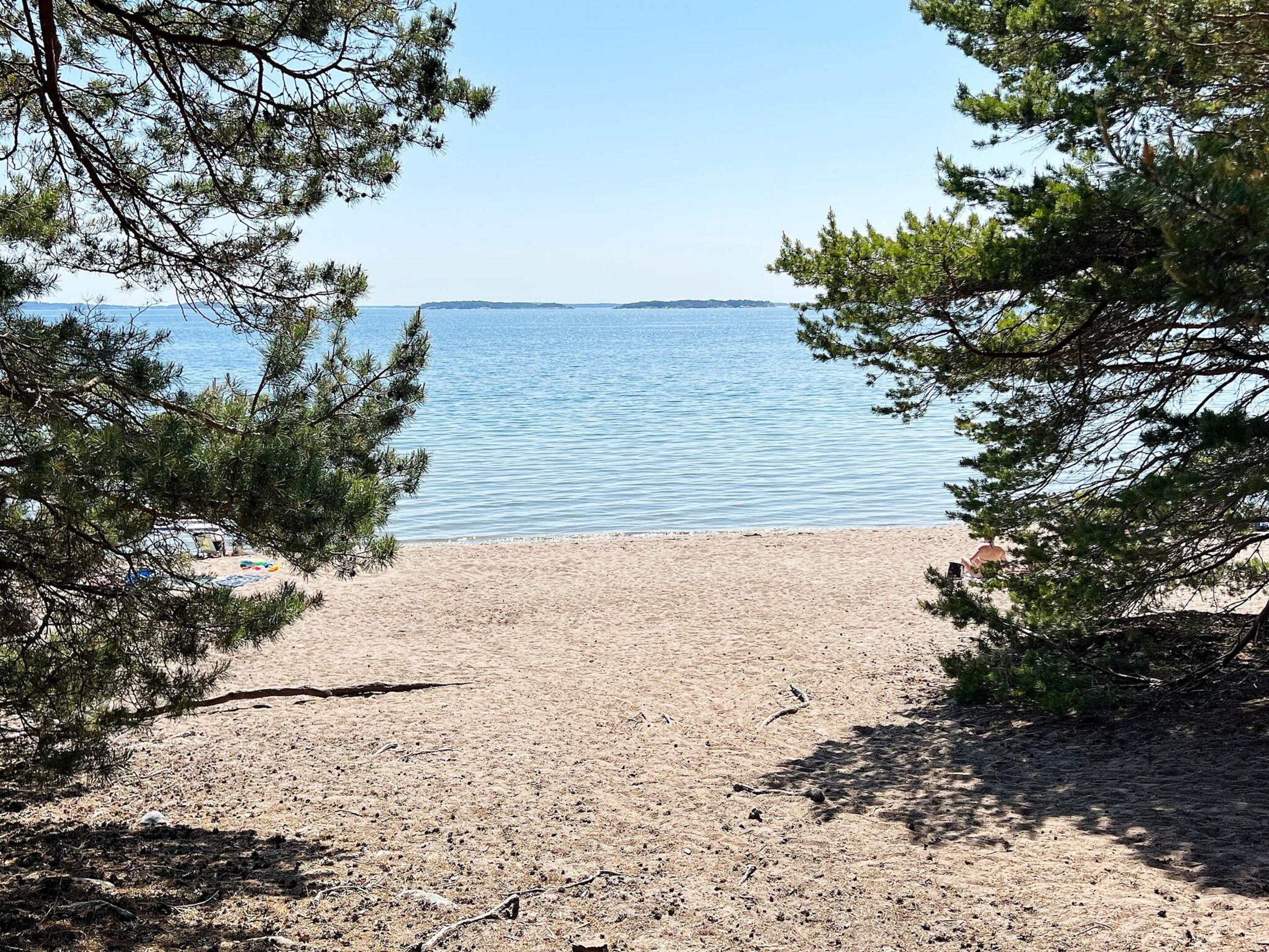 A beach with a clear view of the sea, surrounded by trees.