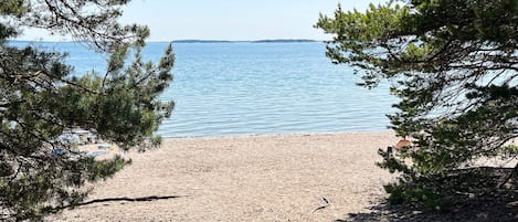 A beach with a clear view of the sea, surrounded by trees.