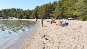 A beach with people relaxing, a sandy shore, and trees in the background. - 4 Star Holiday Home in Ingaro (Ingaro)