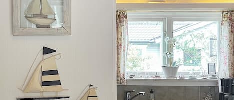 A kitchen with a window, a sink, a coffee maker, and decorative items on the wall.