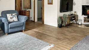 Ein Wohnzimmer mit blauem Sessel, Flachbildfernseher, Kamin und Holzschrank.