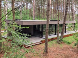 Una casa moderna con fachada de vidrio, rodeada de árboles.