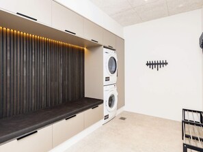 A laundry room with built-in appliances, a bench, and a sound system.
