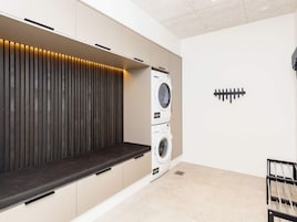 Uma lavanderia equipada com eletrodomésticos embutidos, um banco e um sistema de som.