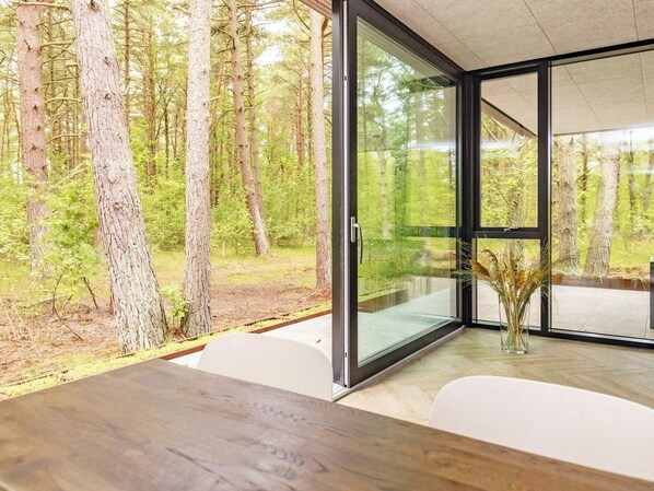 A modern interior with a large glass window offering a view of a forested area.
