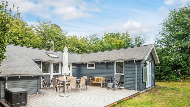 A two-story house with a deck, outdoor seating, and a covered patio area.