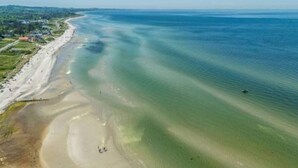 An aerial view of a beach with clear waters and a sandy shore.