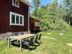 A red wooden building with a table and chairs in front. - 6 Person Holiday Home in Asarum (Asarum)
