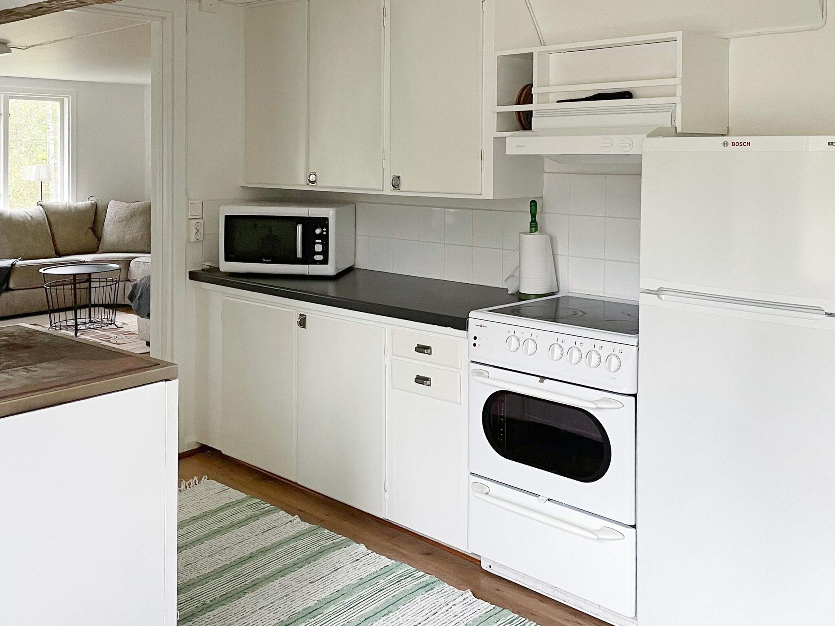 A kitchen with white cabinets, a microwave, an oven, and a refrigerator.