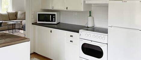 A kitchen with white cabinets, a microwave, an oven, and a refrigerator.