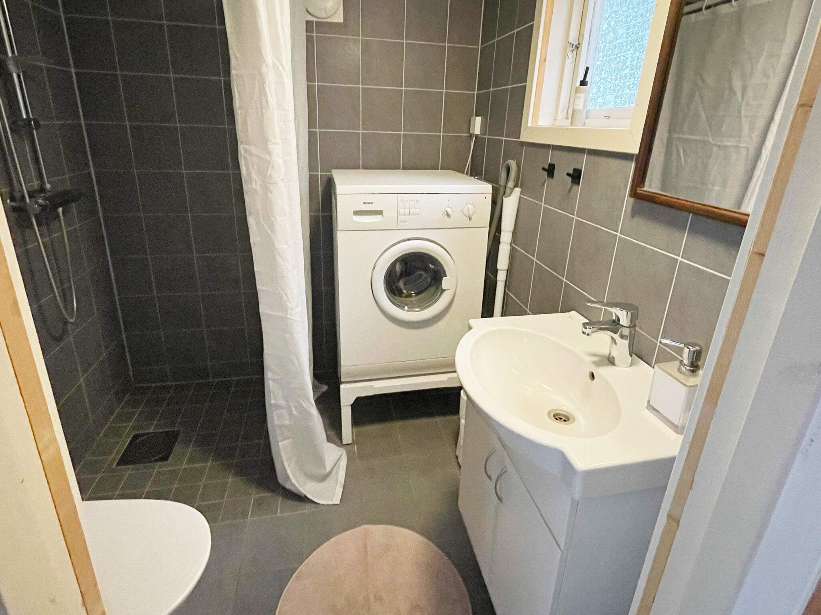 A compact bathroom with a washing machine, a sink, and a toilet.