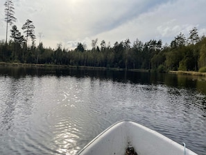 A calm lake with a boat in the foreground and a forested shoreline in the background. - 6 Person Holiday Home in Asarum (Asarum)
