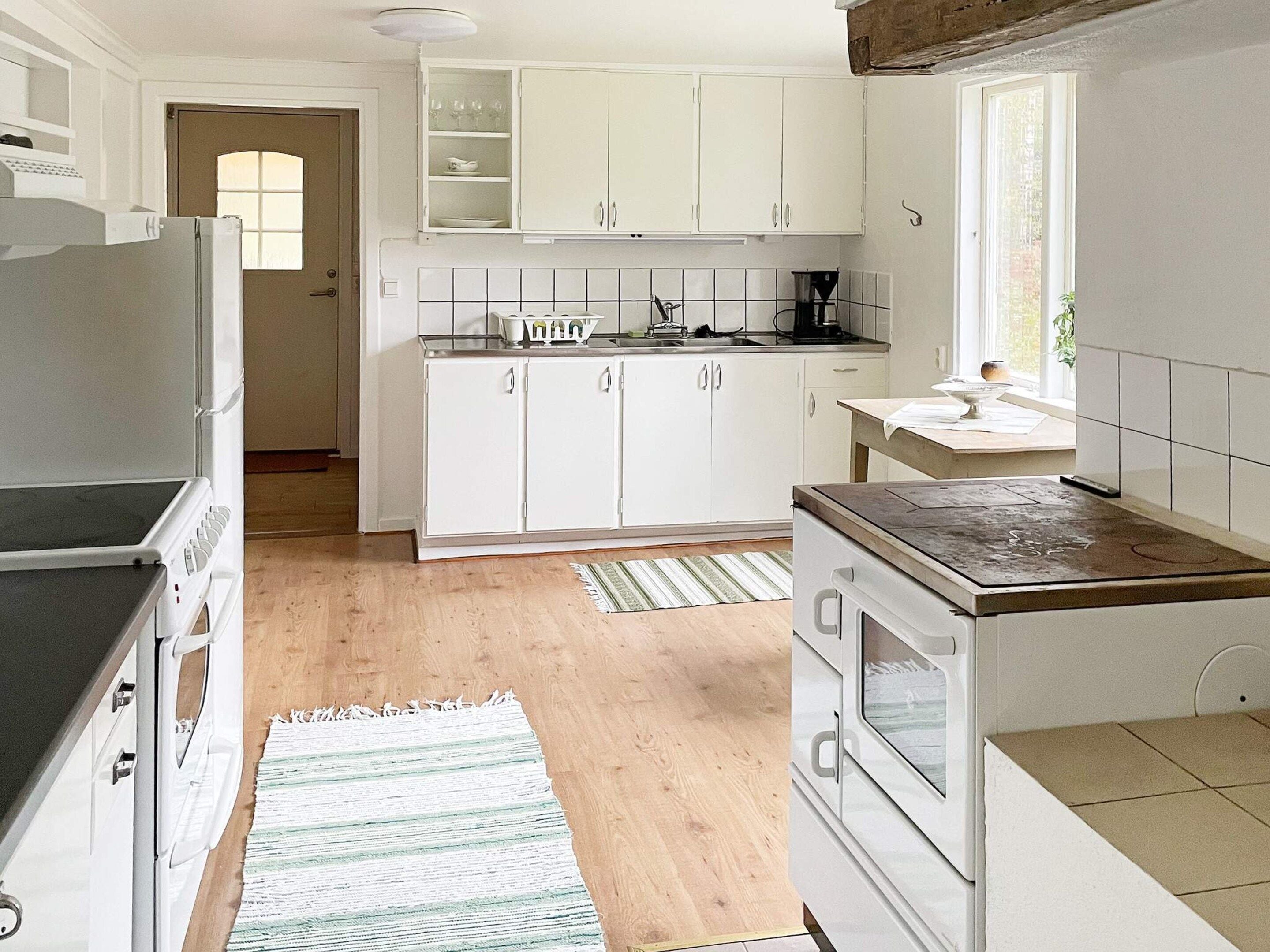 A kitchen with white cabinets, a stove, a refrigerator, and a window providing natural light.