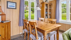 A dining area with a wooden table and chairs, a cabinet, and a cabinet with glass doors.