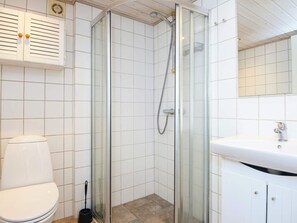Une salle de bain avec une douche à parois de verre, des toilettes blanches et un lavabo avec un miroir au-dessus.