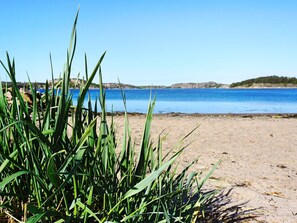 Una spiaggia con acqua cristallina e colline rocciose in lontananza.