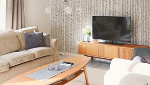 Olohuoneessa on sohva, sohvapöytä, televisio ja kaappi.