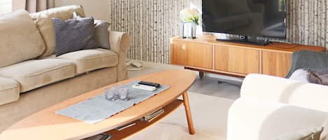 Una sala de estar con un sofá, una mesa de centro, un televisor y un aparador.
