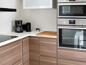 A kitchen with a built-in oven, a coffee maker, and a wooden cutting board. - 6 Person Holiday Home in Skummeslovsstrand (Skummesloevsstrand)