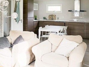 A modern kitchen with a white table and chairs, a refrigerator, and a window above the sink.
