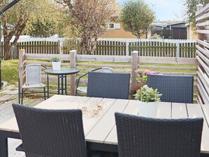 A patio with a table and four chairs, surrounded by a wooden fence and trees. - 6 Person Holiday Home in Skummeslovsstrand (Skummesloevsstrand)