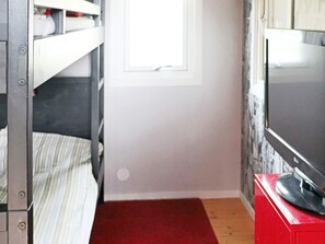 A room with bunk beds, a television on a red stand, and a window. - 6 Person Holiday Home in Skummeslovsstrand (Skummesloevsstrand)