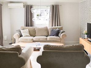 A living room with a beige sofa, a coffee table, and a television on a wooden cabinet. - 6 Person Holiday Home in Skummeslovsstrand (Skummesloevsstrand)