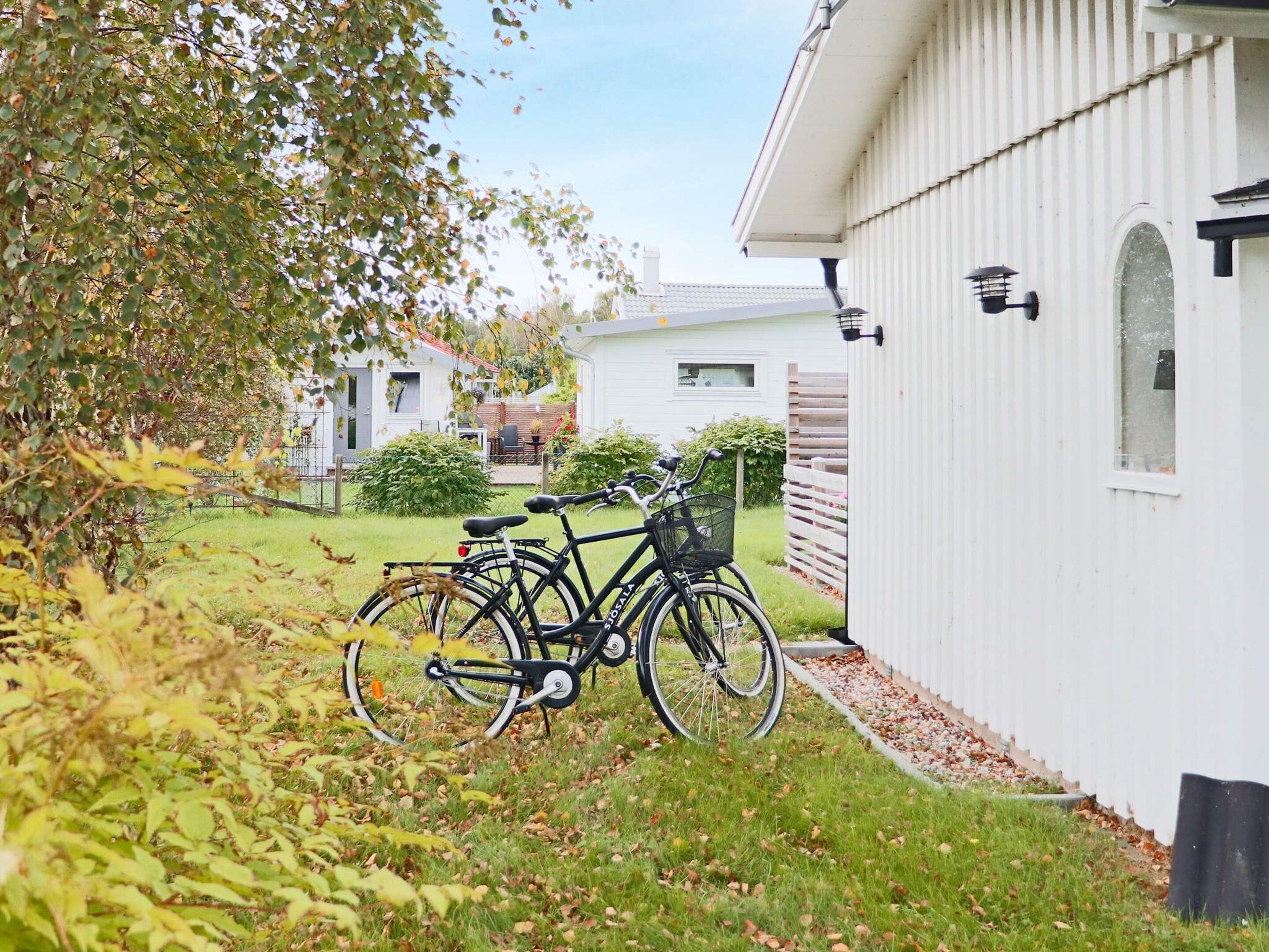 A residential area with a white building, a bicycle parked in front, and a grassy yard.