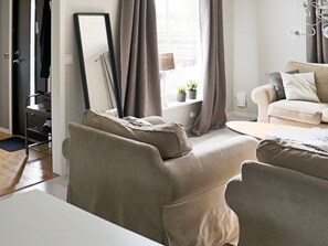 A living room with a sofa, a coffee table, a lamp, and a window with curtains. - 6 Person Holiday Home in Skummeslovsstrand (Skummesloevsstrand)