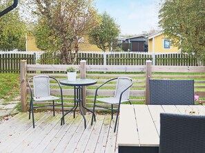 An outdoor patio with a wooden deck, two wicker chairs, a small round table, and a potted plant. - 6 Person Holiday Home in Skummeslovsstrand (Skummesloevsstrand)