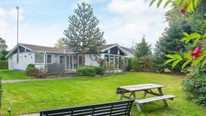 Una casa con un patio, una panchina e un tavolo da picnic.