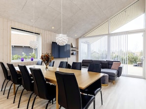 A modern dining area with a wooden table, black chairs, and a sofa. - 5 Star Holiday Home in Vaeggerlose (Vaeggerlose)