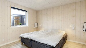 A bedroom with a bed, a window, and a wooden floor. - 5 Star Holiday Home in Vaeggerlose (Vaeggerlose)